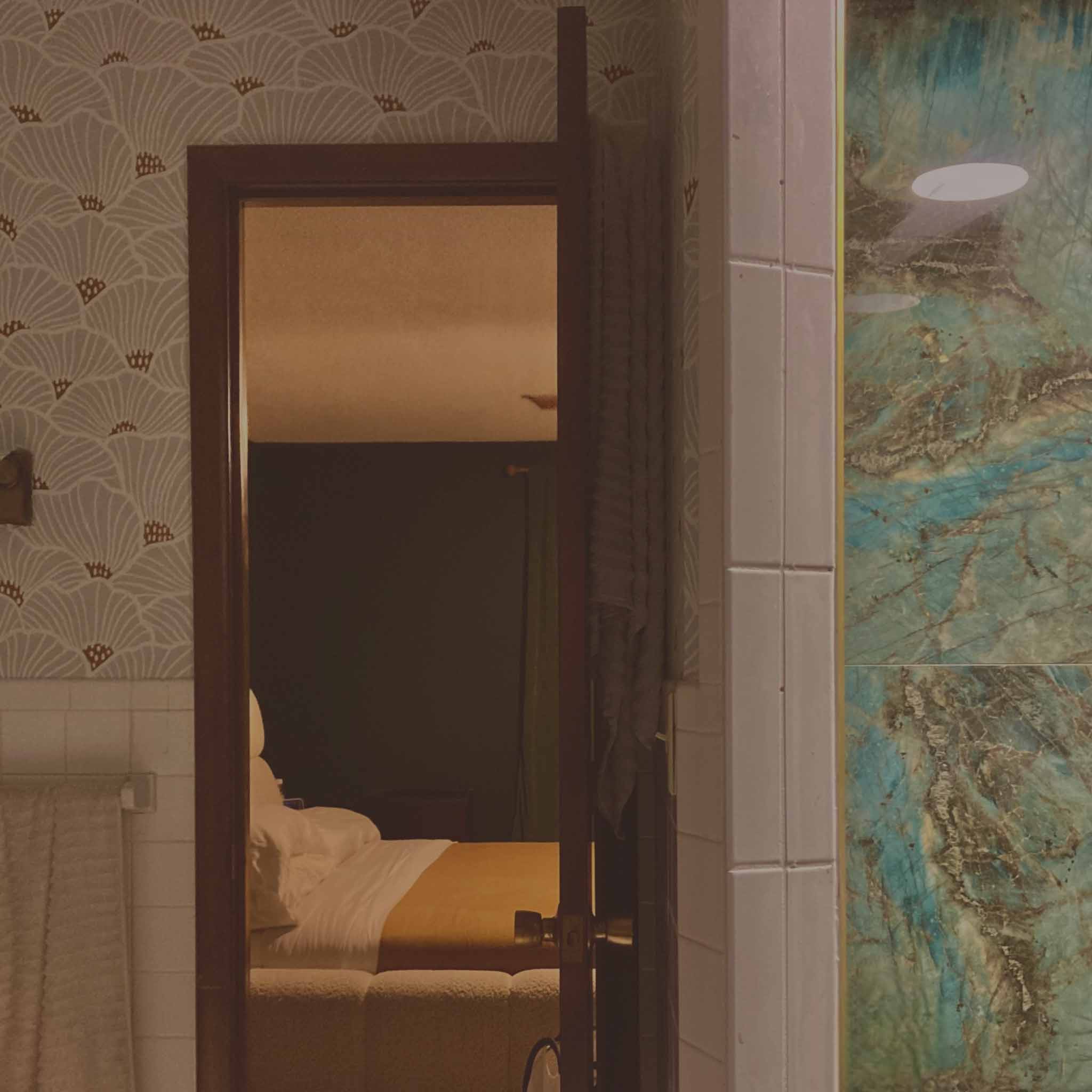 Bathroom doorway with patterned wallpaper and turquoise tile